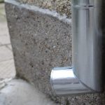 Metal downspout attached to a concrete wall.