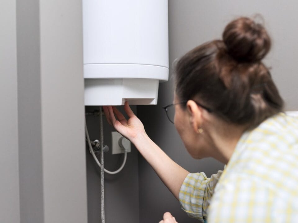 A woman adjusting settings on a wall-mounted boiler during essential maintenance.